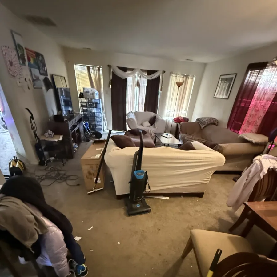 Living room cluttered with laundry and boxes before cleaning